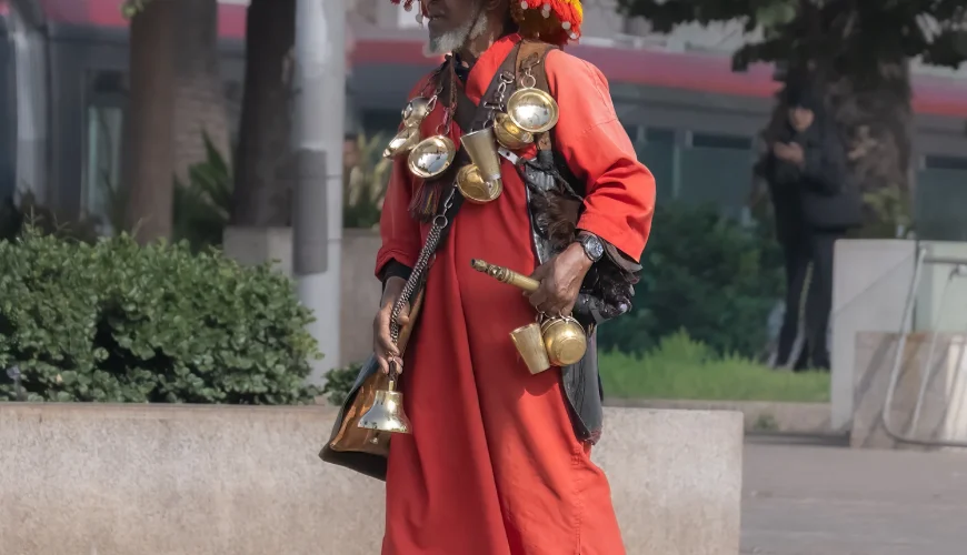 The Traditional Water Seller in Morocco: A Living Symbol of Culture and Heritage Walking through the old medinas of Morocco—especially in cities like Marrakech, Fes, Rabat, and Meknes—you may encounter a striking figure dressed in colorful traditional clothing, carrying brass cups and a decorated water container. This is the traditional Moroccan water seller, one of the most iconic symbols of Morocco’s rich cultural heritage. A Tradition Rooted in History The profession of the water seller dates back centuries, long before modern plumbing existed in Moroccan cities. At that time, access to fresh drinking water was limited, and water sellers played a vital role in daily life by providing clean water to locals, travelers, and merchants in the medina. They would collect water from natural springs, fountains, or public wells and distribute it throughout the city. Their presence ensured survival in Morocco’s warm climate and became an essential service within urban life. More Than a Job – A Cultural Identity Today, the water seller is no longer a necessity but remains a living tradition and an important part of Moroccan identity. You will often see them near busy squares, historic sites, or tourist areas, especially in Jemaa el-Fnaa Square in Marrakech, where culture, history, and daily life blend together. Their traditional outfit—often featuring a wide-brimmed hat adorned with colorful tassels—along with the sound of clinking metal cups, attracts visitors and photographers from around the world. A Symbol of Authentic Morocco For travelers seeking authentic Moroccan experiences, encountering a water seller is a reminder of Morocco’s deep respect for tradition and heritage. It reflects a time when community, simplicity, and human connection were at the heart of everyday life. Taking a photo with a water seller is not just a travel moment—it is a connection to Morocco’s past, preserved in the present. Experiencing Local Life with Moroccan Odyssey At Moroccan Odyssey, we believe true travel goes beyond monuments and landscapes. We design private and customized tours that immerse our guests in Morocco’s local traditions, daily life, and cultural stories. From walking through ancient medinas to meeting local artisans and witnessing timeless traditions like the water seller, our tours offer a deeper understanding of Morocco—guided by knowledgeable locals who share the heart of the country.