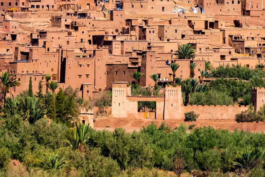 Aït Ben Haddou: Morocco’s Iconic UNESCO World Heritage Kasbah Standing proudly along the ancient caravan route between the Sahara Desert and Marrakech, Aït Ben Haddou is one of Morocco’s most remarkable historic sites. This stunning ksar (fortified village), built from earth and clay, is a powerful symbol of Morocco’s architectural heritage and a true gateway to the country’s southern history. A Journey Through History Aït Ben Haddou dates back to at least the 11th century and served as a vital stop for traders transporting gold, salt, spices, and slaves across the Sahara. Its strategic location allowed caravans to rest, trade, and protect their goods before continuing toward the imperial cities of Morocco. The village is made up of closely packed kasbahs, surrounded by high defensive walls and corner towers decorated with traditional Berber motifs. This unique earthen architecture reflects centuries of knowledge adapted to the desert climate. UNESCO World Heritage Site In 1987, Aït Ben Haddou was recognized as a UNESCO World Heritage Site, highlighting its outstanding cultural value and exceptional preservation. Today, it remains one of the best-preserved examples of traditional pre-Saharan architecture in Morocco. Ongoing restoration efforts help protect this historic site while allowing visitors to experience its authentic atmosphere. Aït Ben Haddou in Film and Popular Culture Aït Ben Haddou’s dramatic landscape has made it a favorite filming location for international cinema. It has appeared in famous productions such as Gladiator, Game of Thrones, Lawrence of Arabia, and The Mummy. Walking through its narrow alleys feels like stepping into a living movie set where history and storytelling merge. Visiting Aït Ben Haddou Today Visitors can explore the village on foot, crossing the river and climbing to the top for breathtaking panoramic views of the surrounding desert and Atlas Mountains. Small homes, ancient granaries, and quiet courtyards reveal a way of life that has endured for generations. Though only a few families still live inside the ksar, Aït Ben Haddou remains a powerful reminder of Morocco’s past and a highlight of any journey through the south. Experience Aït Ben Haddou with Moroccan Odyssey At Moroccan Odyssey, we include Aït Ben Haddou in many of our private and customized tours through southern Morocco. Our expert local guides share the hidden stories, history, and cultural significance of this extraordinary site, turning your visit into a meaningful experience rather than just a photo stop. Whether traveling from Marrakech to the Sahara Desert or exploring the Atlas Mountains, Aït Ben Haddou is an essential stop that brings Morocco’s history to life. Why Aït Ben Haddou Should Be on Your Morocco Itinerary • UNESCO World Heritage Site • Unique earthen kasbah architecture • Rich Berber and caravan history • Famous movie and TV filming location • Stunning desert and mountain scenery