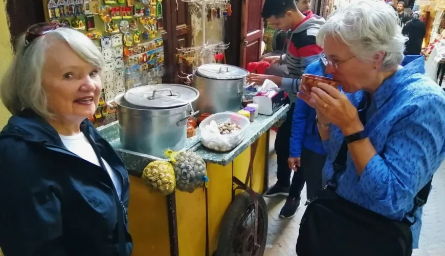 Guests enjoying traditional Moroccan snail soup during a Fes street food tasting in the old medina