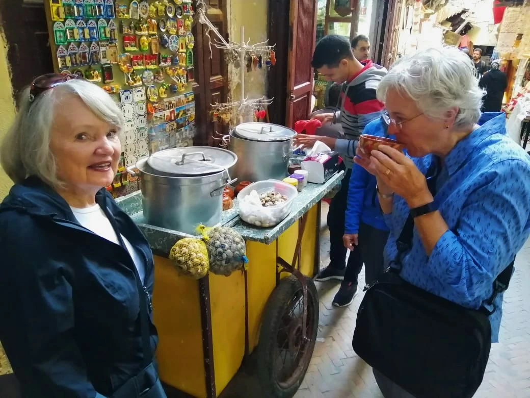 Guests enjoying traditional Moroccan snail soup during a Fes street food tasting in the old medina