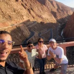 Nestled between rugged red-rock mountains in the south of Morocco, Dades Gorge is one of the country’s most breathtaking natural wonders. Known for its dramatic landscapes, deep valleys, and impressive rock formations, this region is a highlight for travelers seeking adventure, beauty, and authentic Moroccan culture. One of the most iconic attractions inside the Dades Valley is the Amsmimer Zigzag Road, often called the “Tizi n’Tissdrine Road” — a serpentine stretch of mountain road famous for its sharp bends and extraordinary panoramic views. For many visitors, the journey through the Dades Gorge feels like stepping into another world. Towering canyon walls rise dramatically on both sides, shaped over thousands of years by the Dades River. This unique landscape attracts photographers, nature lovers, and travelers in search of untouched beauty. When exploring this region on a private tour in Morocco, the experience becomes deeper and more personal, offering guests the chance to discover hidden viewpoints, local villages, and Berber traditions along the way. During one of our recent adventures with Moroccan Odyssey, our guide accompanied three wonderful guests from Indonesia — Dwi, Drazat, and Fendi. The group enjoyed a sunny afternoon at one of the most spectacular viewpoints overlooking the zigzag mountain road of Amsmimer. Their joyful expressions, big smiles, and excitement captured the true spirit of travel: connection, happiness, and the thrill of discovering a new destination. The picture taken at this viewpoint shows the group standing above the winding road, surrounded by the warm colors of the Dades mountains. The dramatic curves of the road make the scene unforgettable and represent the adventurous essence of the Moroccan south. This moment reflects the high-quality, personalized service that Moroccan Odyssey offers on every private tour, ensuring that guests feel safe, guided, and inspired throughout the journey. Exploring the Dades Gorge with Moroccan Odyssey also provides travelers with exclusive access to storytelling, local experiences, and cultural insights. Our guides are passionate about sharing the history of the region, the geology of the canyon, and the traditional life of the Amazigh communities who have lived here for centuries. Whether visitors are traveling as families, friends, couples, or solo explorers, the scenic routes of Dades Valley always leave a lasting memory. If you are planning a trip to Morocco and want to immerse yourself in the beauty of the south — from the High Atlas Mountains to the Sahara Desert — the Dades Gorge and its famous zigzag road should be at the top of your list. And with Moroccan Odyssey, your private tour will be designed with care, comfort, and authenticity. We ensure that every guest, like Dwi, Drazat, and Fendi, experiences Morocco in the most unforgettable way. Exploring the Iconic Dades Gorge Zigzag Road in South Morocco – Private Guided Tour with Moroccan Odyssey and Indonesian Guests Dwi, Drazat & Fendi Private Morocco Tour Through the Dades Gorge and Amsmimer Zigzag Road – Stunning Mountain Experience with Moroccan Odyssey and Guests Dwi, Drazat & Fendi from Indonesia Unforgettable Dades Gorge Experience on the Iconic Zigzag Road – Epic South Morocco Adventure with Moroccan Odyssey and Indonesian Guests Dwi, Drazat & Fend