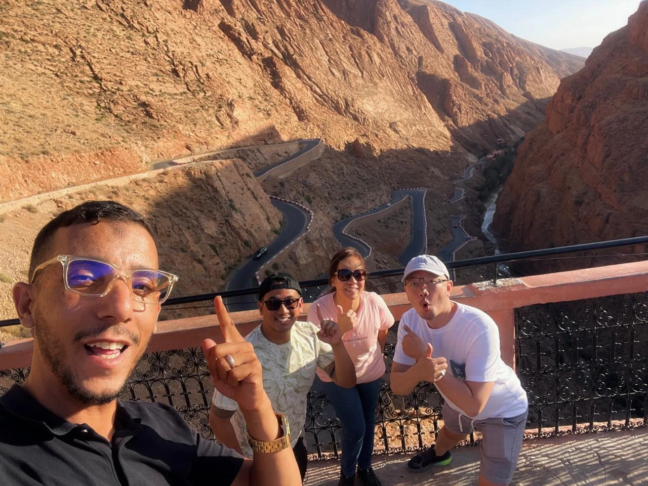 Nestled between rugged red-rock mountains in the south of Morocco, Dades Gorge is one of the country’s most breathtaking natural wonders. Known for its dramatic landscapes, deep valleys, and impressive rock formations, this region is a highlight for travelers seeking adventure, beauty, and authentic Moroccan culture. One of the most iconic attractions inside the Dades Valley is the Amsmimer Zigzag Road, often called the “Tizi n’Tissdrine Road” — a serpentine stretch of mountain road famous for its sharp bends and extraordinary panoramic views. For many visitors, the journey through the Dades Gorge feels like stepping into another world. Towering canyon walls rise dramatically on both sides, shaped over thousands of years by the Dades River. This unique landscape attracts photographers, nature lovers, and travelers in search of untouched beauty. When exploring this region on a private tour in Morocco, the experience becomes deeper and more personal, offering guests the chance to discover hidden viewpoints, local villages, and Berber traditions along the way. During one of our recent adventures with Moroccan Odyssey, our guide accompanied three wonderful guests from Indonesia — Dwi, Drazat, and Fendi. The group enjoyed a sunny afternoon at one of the most spectacular viewpoints overlooking the zigzag mountain road of Amsmimer. Their joyful expressions, big smiles, and excitement captured the true spirit of travel: connection, happiness, and the thrill of discovering a new destination. The picture taken at this viewpoint shows the group standing above the winding road, surrounded by the warm colors of the Dades mountains. The dramatic curves of the road make the scene unforgettable and represent the adventurous essence of the Moroccan south. This moment reflects the high-quality, personalized service that Moroccan Odyssey offers on every private tour, ensuring that guests feel safe, guided, and inspired throughout the journey. Exploring the Dades Gorge with Moroccan Odyssey also provides travelers with exclusive access to storytelling, local experiences, and cultural insights. Our guides are passionate about sharing the history of the region, the geology of the canyon, and the traditional life of the Amazigh communities who have lived here for centuries. Whether visitors are traveling as families, friends, couples, or solo explorers, the scenic routes of Dades Valley always leave a lasting memory. If you are planning a trip to Morocco and want to immerse yourself in the beauty of the south — from the High Atlas Mountains to the Sahara Desert — the Dades Gorge and its famous zigzag road should be at the top of your list. And with Moroccan Odyssey, your private tour will be designed with care, comfort, and authenticity. We ensure that every guest, like Dwi, Drazat, and Fendi, experiences Morocco in the most unforgettable way. Exploring the Iconic Dades Gorge Zigzag Road in South Morocco – Private Guided Tour with Moroccan Odyssey and Indonesian Guests Dwi, Drazat & Fendi Private Morocco Tour Through the Dades Gorge and Amsmimer Zigzag Road – Stunning Mountain Experience with Moroccan Odyssey and Guests Dwi, Drazat & Fendi from Indonesia Unforgettable Dades Gorge Experience on the Iconic Zigzag Road – Epic South Morocco Adventure with Moroccan Odyssey and Indonesian Guests Dwi, Drazat & Fend