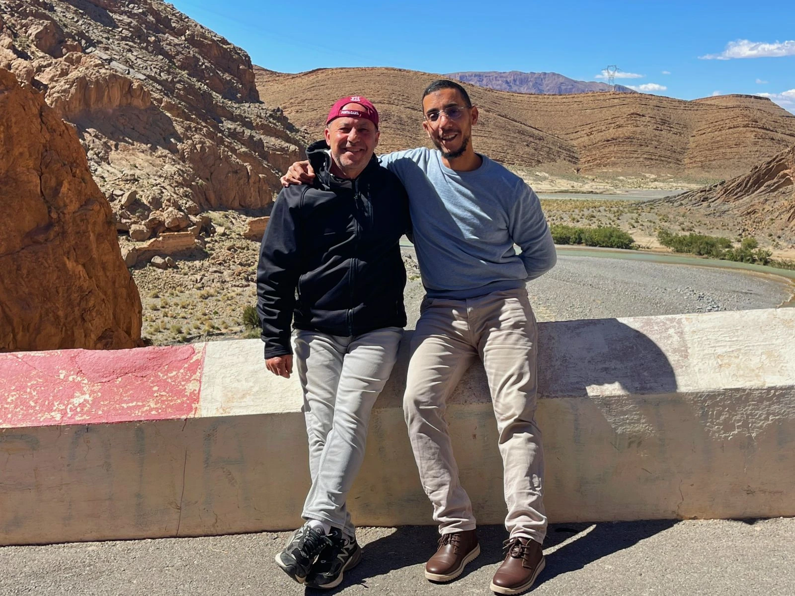 Guest and local guide enjoying a scenic stop in Dades Valley, Morocco, with stunning mountain landscapes and river views during a private desert tour