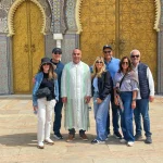 Group of travelers enjoying a private cultural tour in Fes Morocco in front of the magnificent Royal Palace gates with traditional Moroccan architecture.