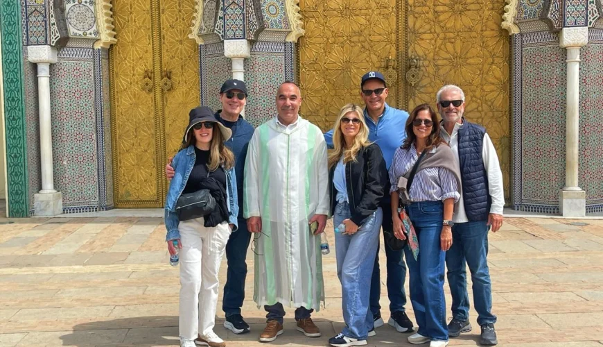 Group of travelers enjoying a private cultural tour in Fes Morocco in front of the magnificent Royal Palace gates with traditional Moroccan architecture.