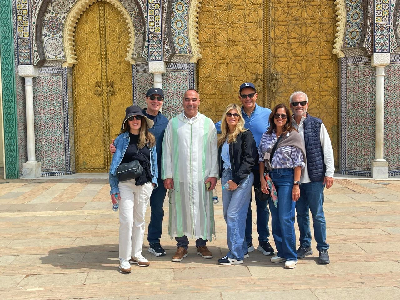 Group of travelers enjoying a private cultural tour in Fes Morocco in front of the magnificent Royal Palace gates with traditional Moroccan architecture.