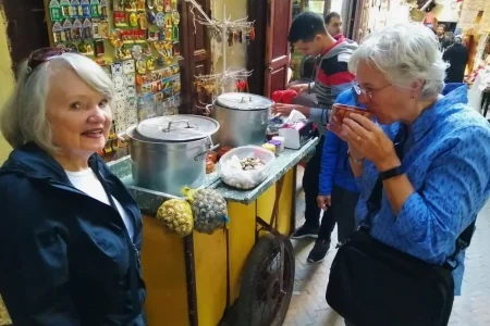 Guests enjoying traditional Moroccan snail soup in a local market setting.